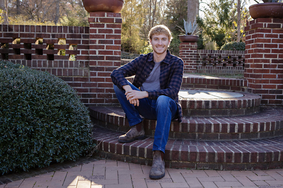 Confident fall portrait of young man in patterned shirt on brick steps at UNCC Botanical Garden