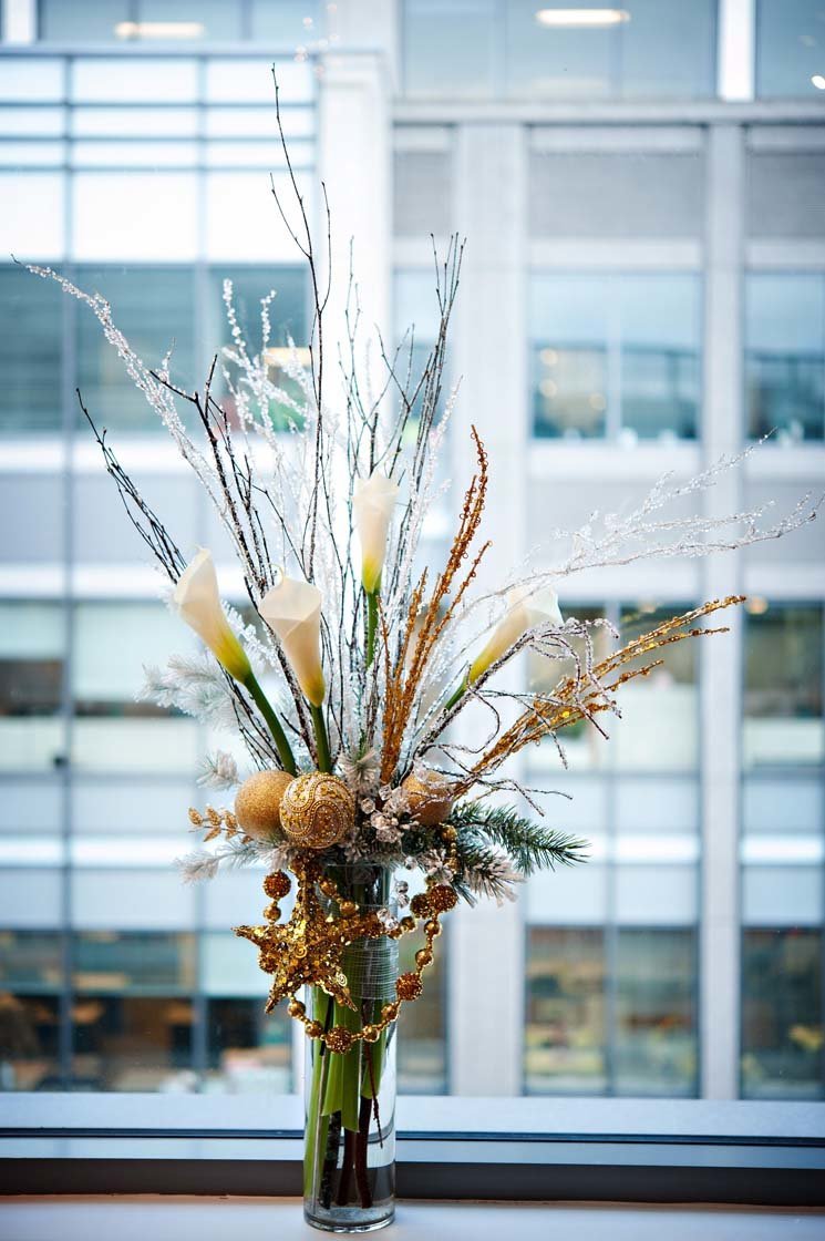 centerpiece for corporate holiday party centerpiece with white callas, gold ornaments, in tall glass vase and sparkly branches
