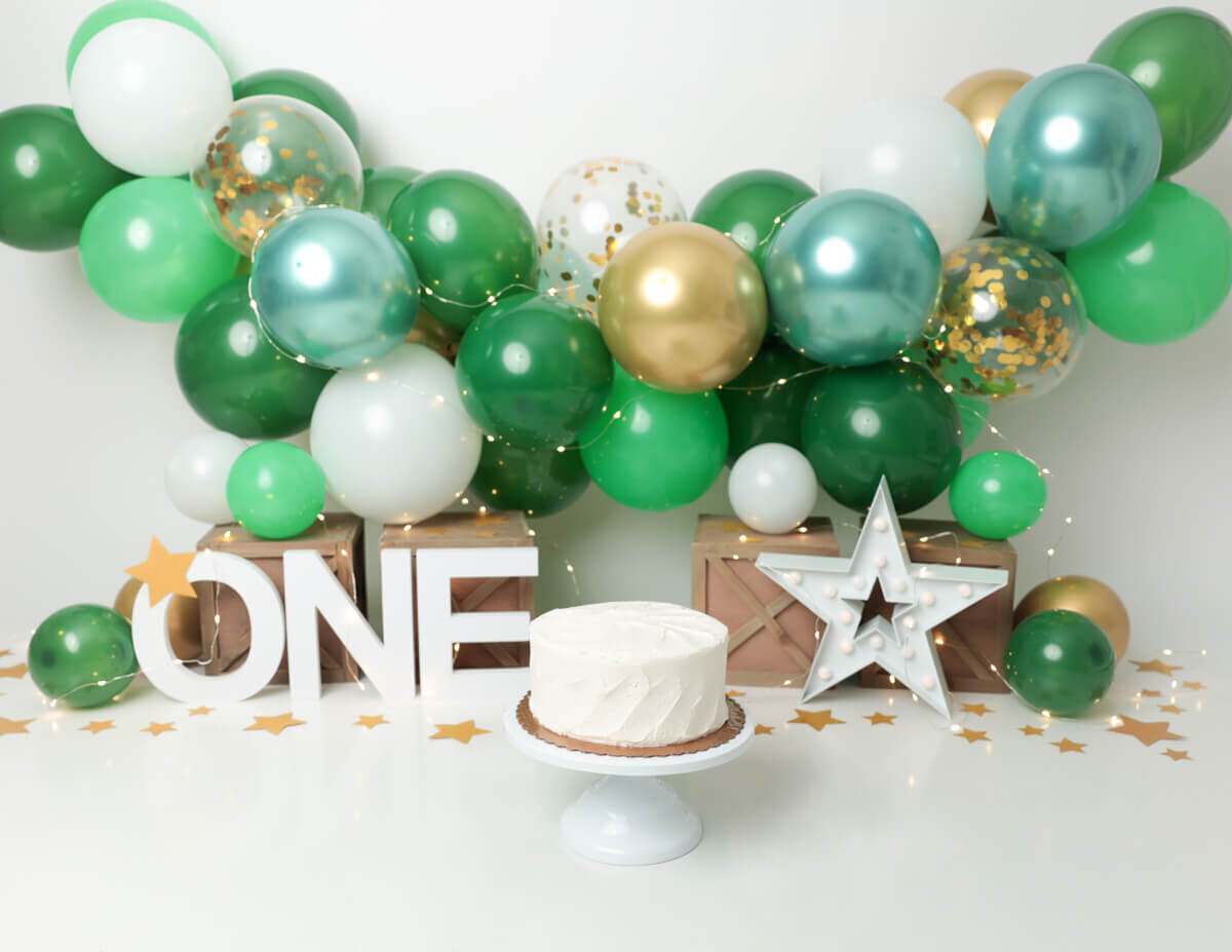 A cake smash moment featuring  festive green and gold balloons in Rochester, NY.