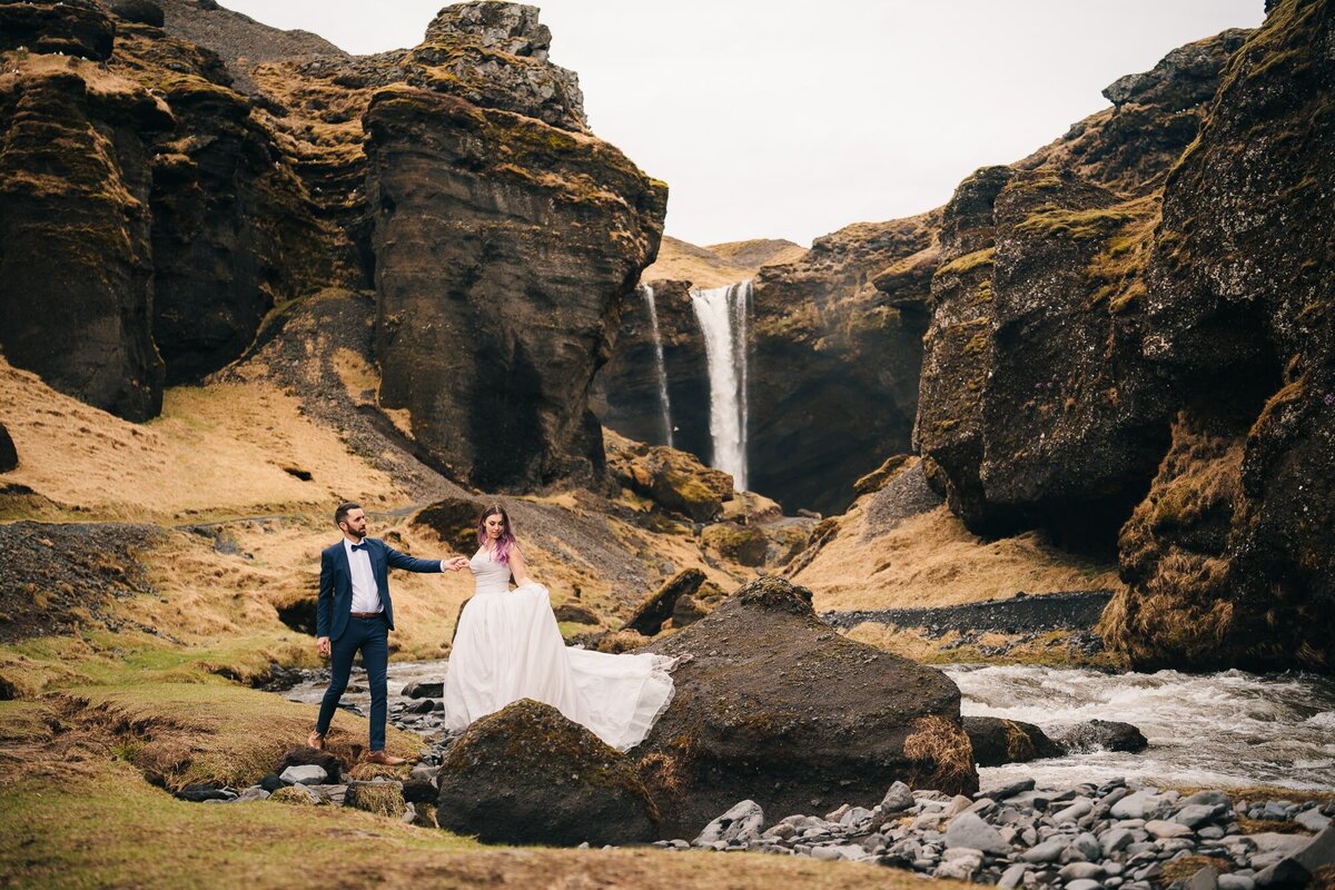 Iceland Waterfalls provide a mesmerizing backdrop as this eloping couple walks hand in hand, creating an unforgettable and romantic moment.