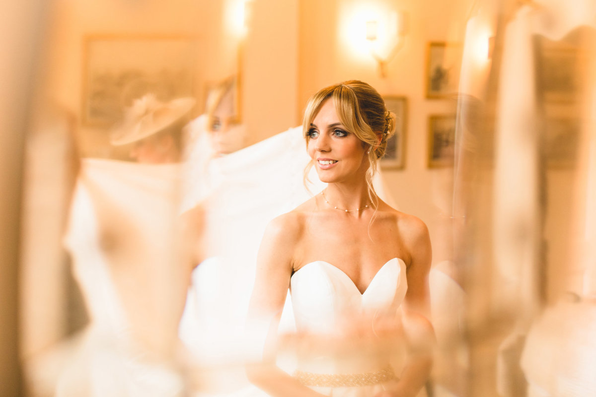 Photograph of a bride taken in the mirror at Iscoyd Park bridal suite at the Brian looks out of the window