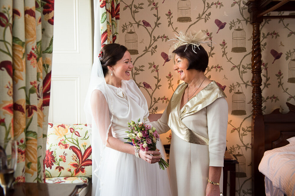 bride wearing an a-line silk and tulle wedding dress looking at her mother wearing a cream dress while standing in the bridal suite of Ballyseede Castle