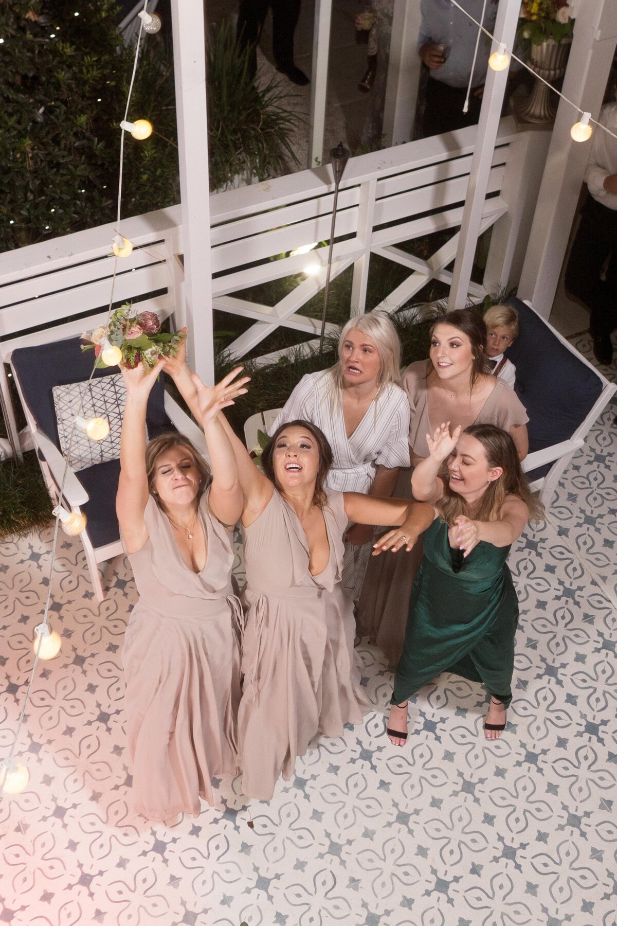 The bridesmaids attempt to catch the bouquet.