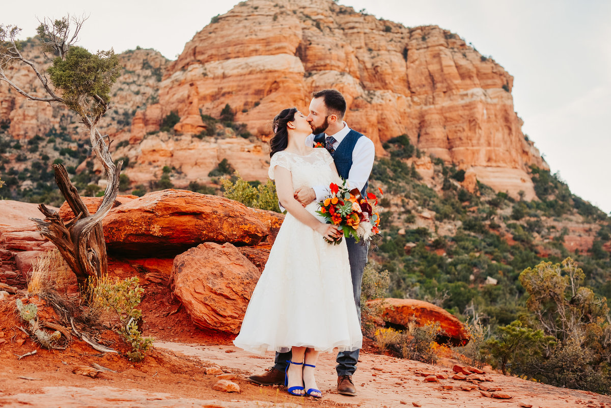 Bride and Groom kissing on red rocks Sedona colorful wedding elopement