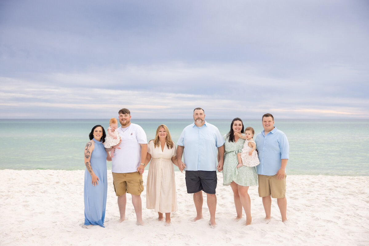 A family standing next to each other smiling at the beach