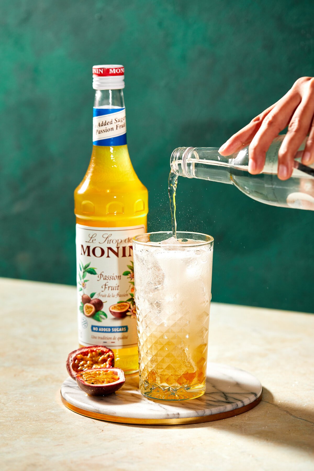 A woman pouring a sparkling soda into a passion fruit drink.