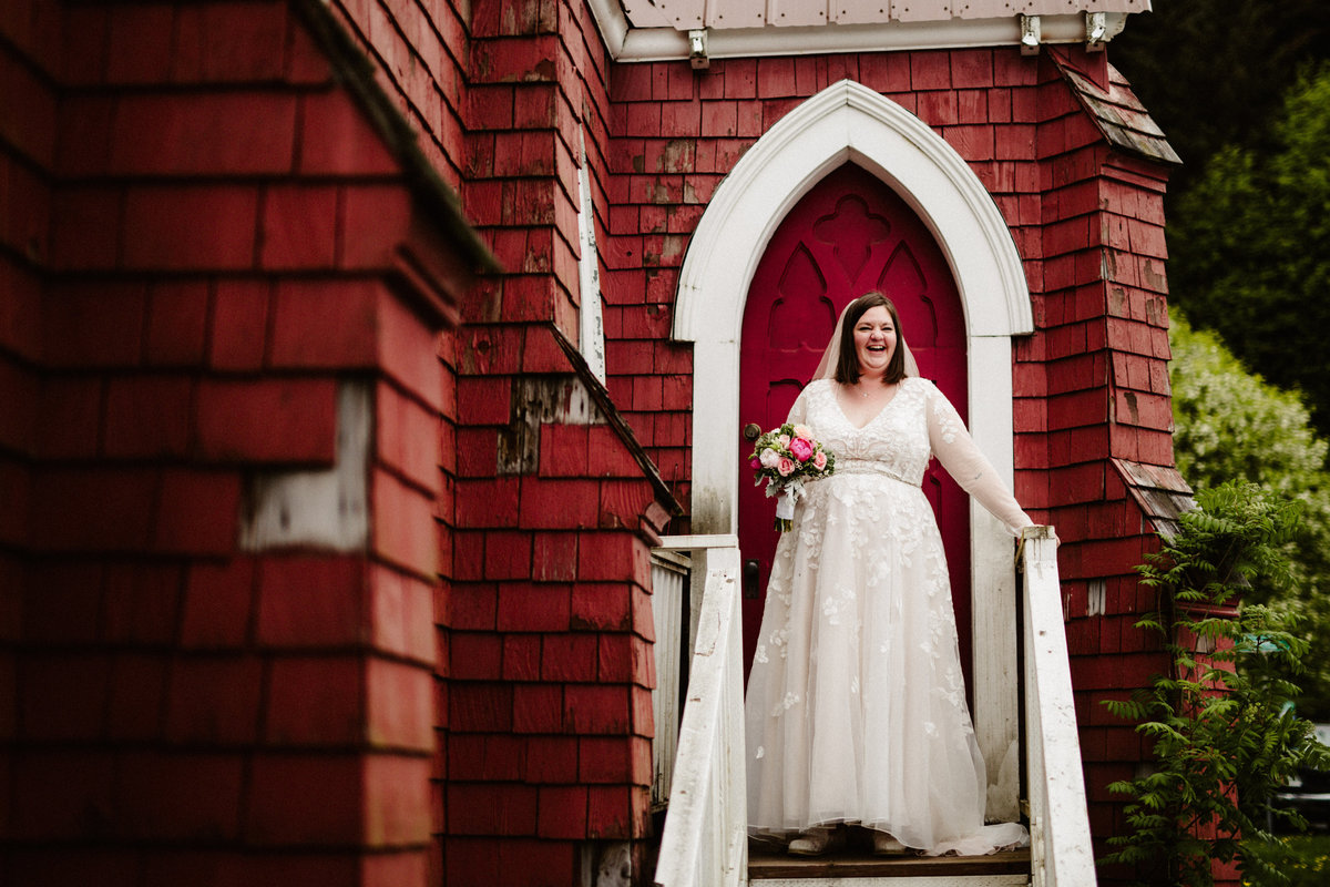 bride laughs on steps of st.peter's episcopal church in seward