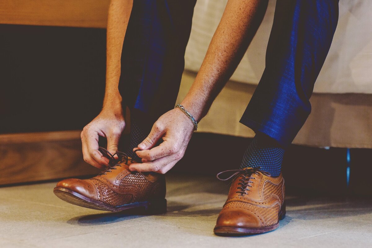 Groom doing up his shoes for wedding in Cancun