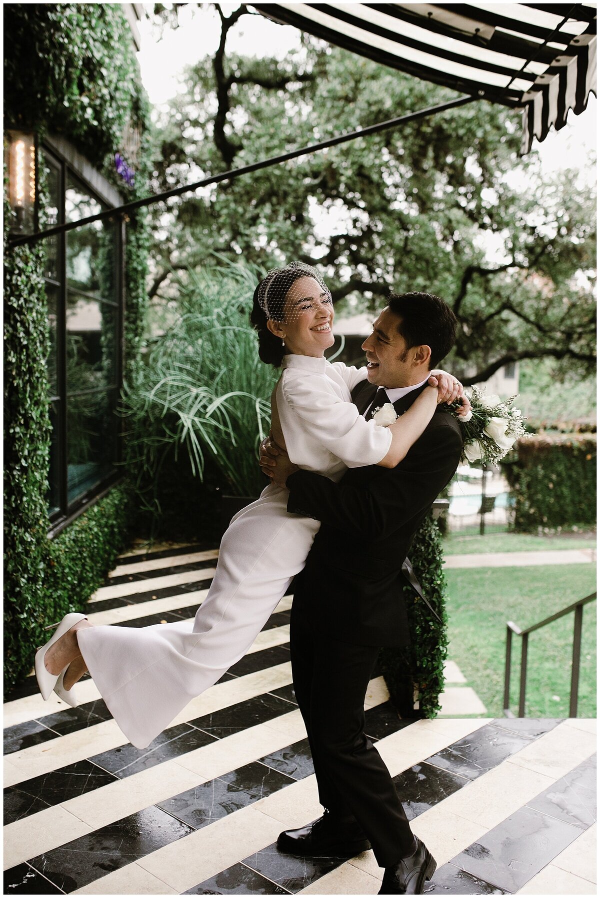 Groom holding bride up in the grounds of Hotel Saint Cecilia  Austin