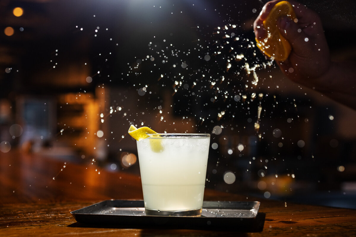 Lemon being squeezed onto a cocktail