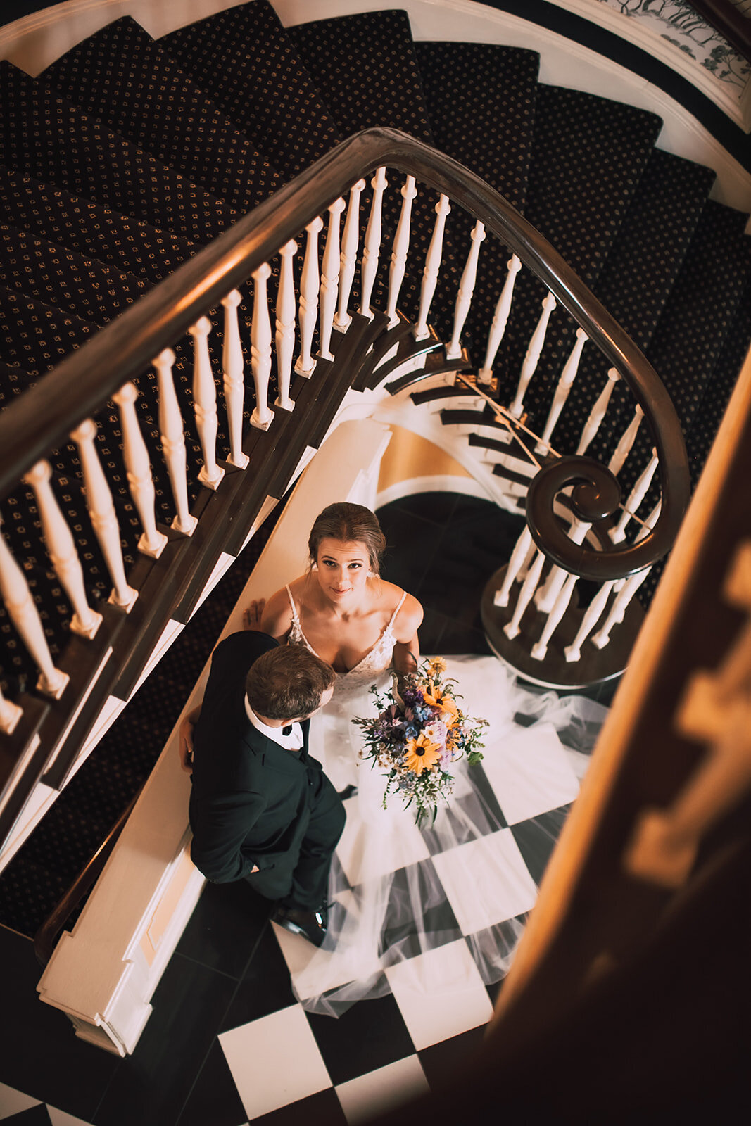 Bride gazes up at camera from bottom of staircase