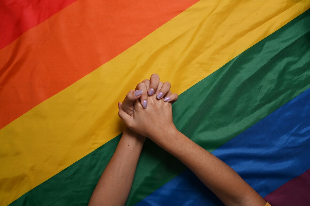 woman's hands laying on top of a rainbow flag