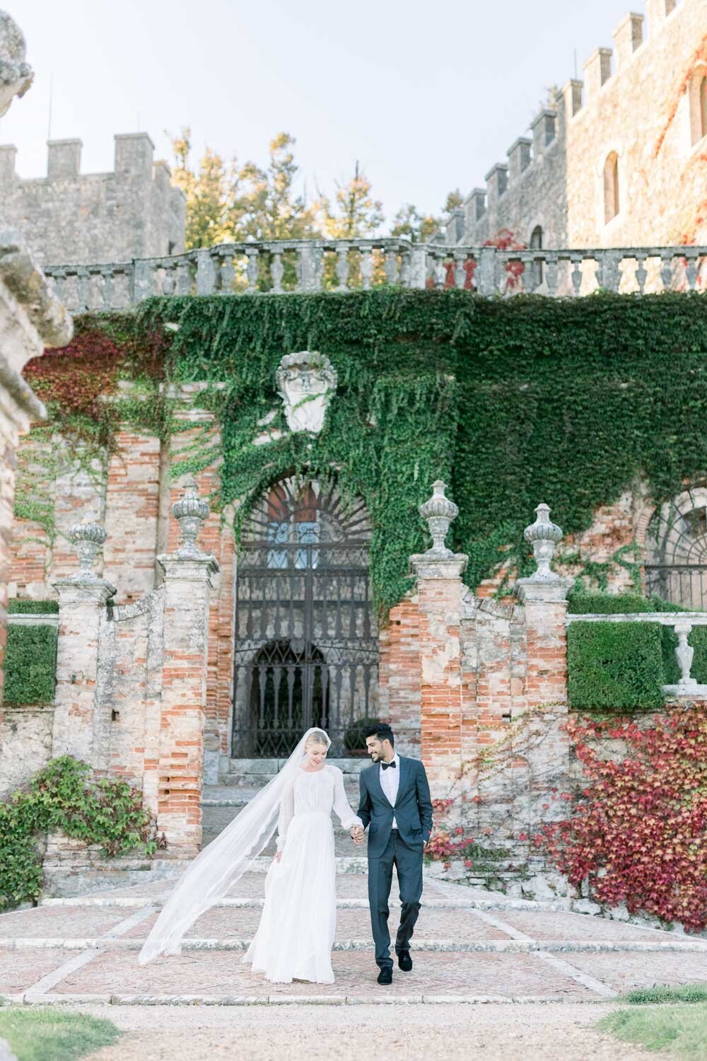 bride and groom walking in front of castello di celsa