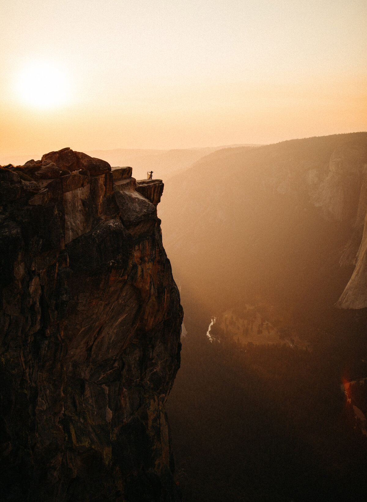 Bride walking toward edge of cliff at Taft Point in Yosemite during sunset