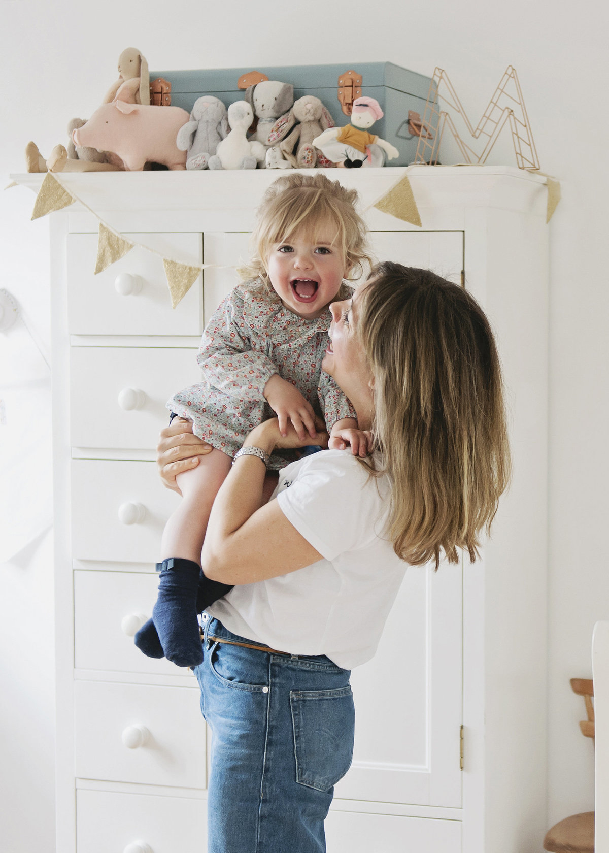 A mother cuddles with her child in a pretty nursery during an at-home family photo shoot in London