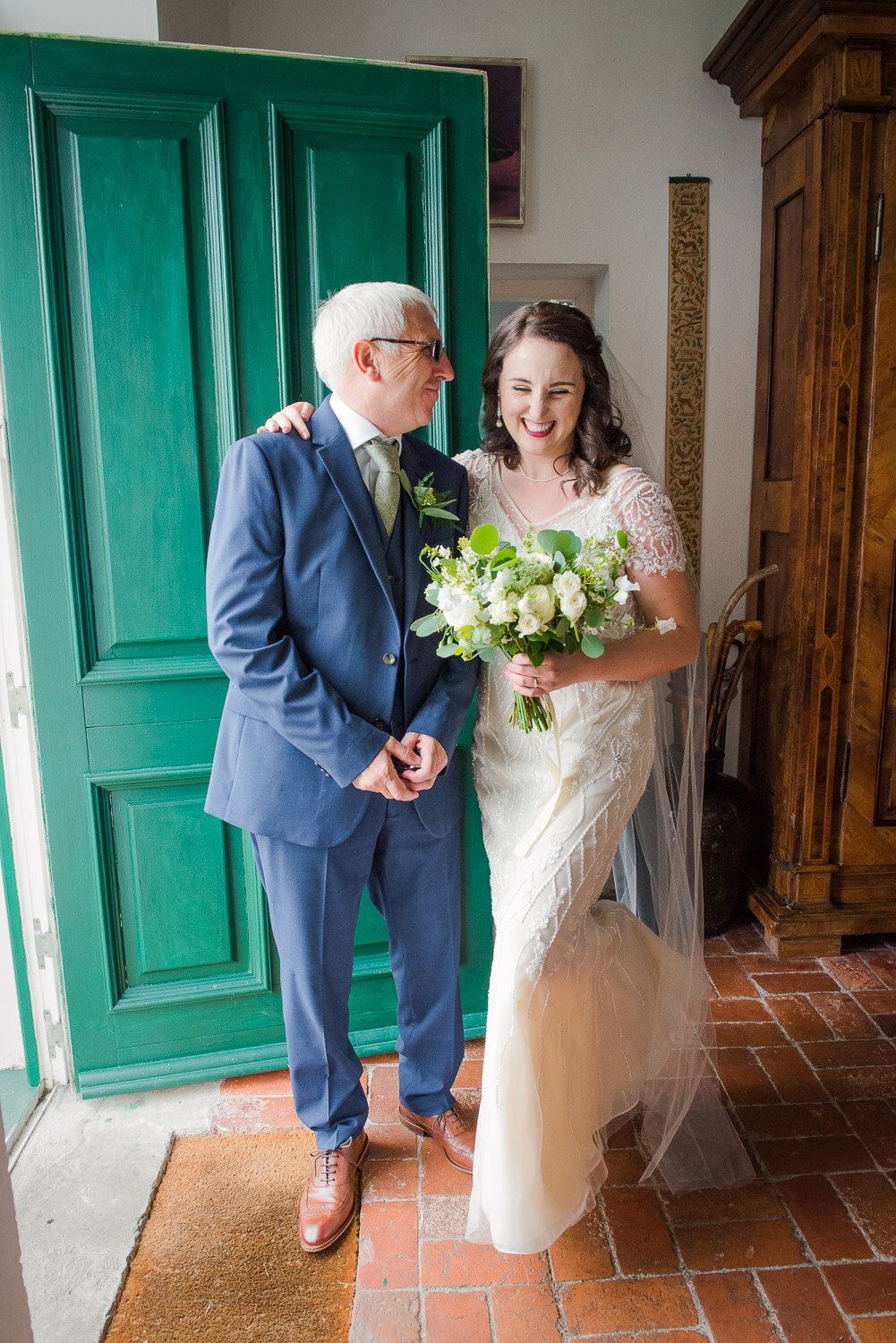 brunette bride in vintage, beaded wedding dress sharing a moment with her father in law at the door of Westcove House