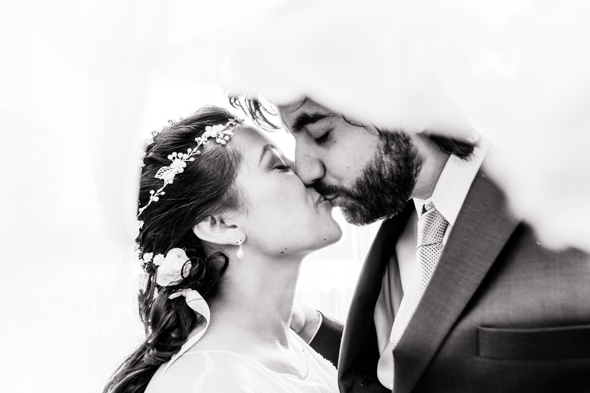 Black and white image of just married bride and groom sharing a tender and romantic kiss