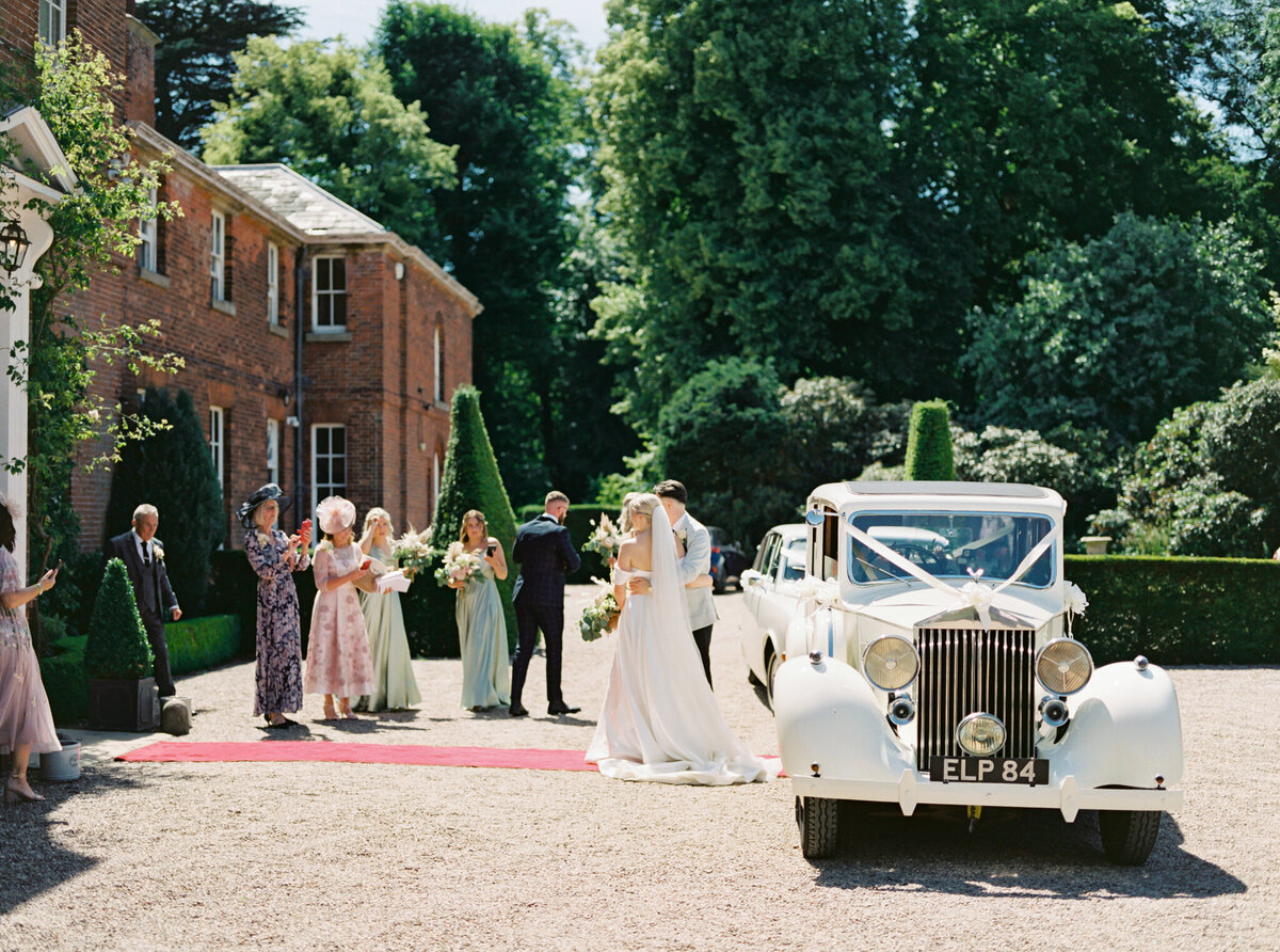 bride and groom arriving at the wedding venue in the vintage car and greeting with parents and siblings