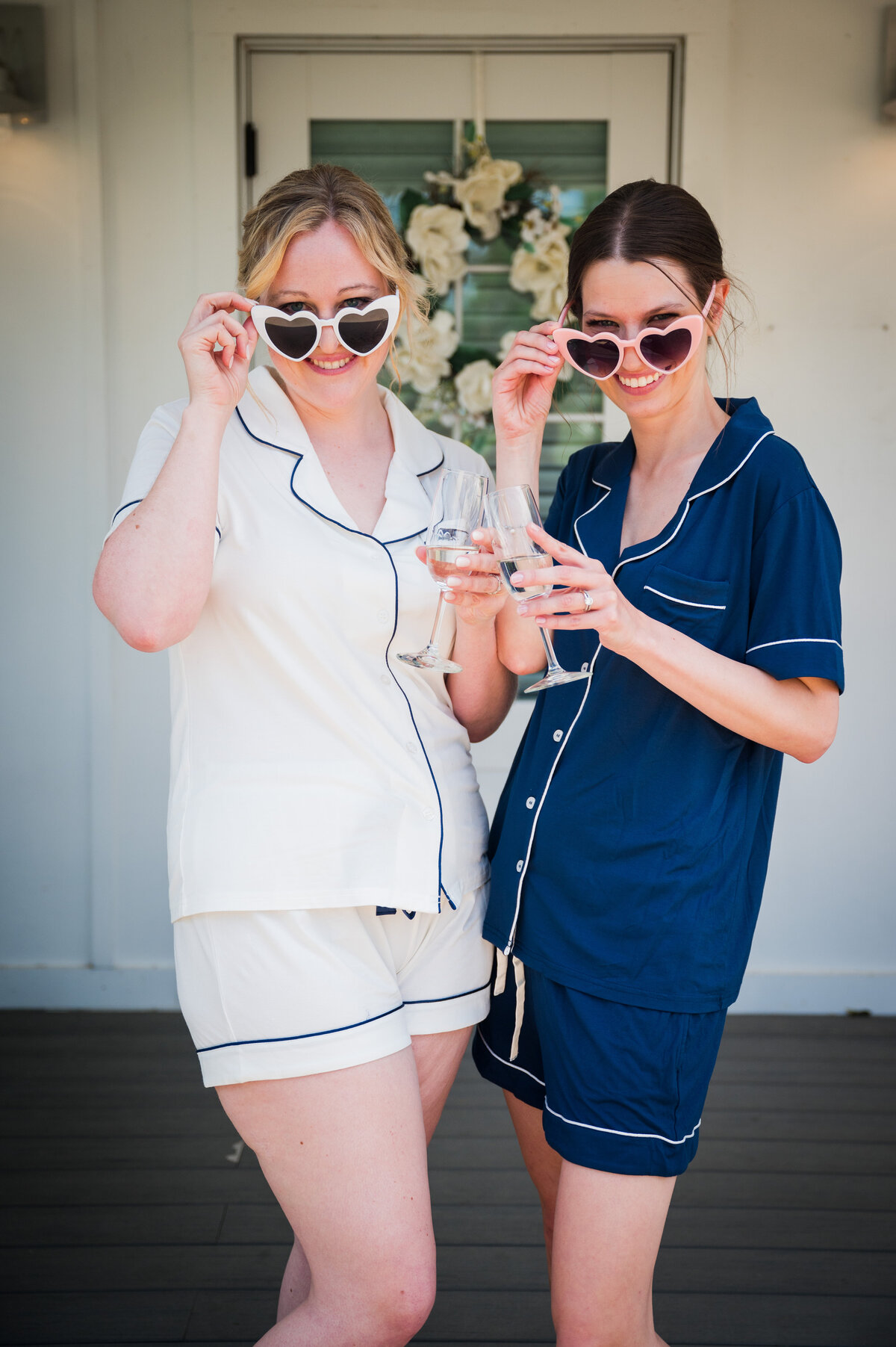 A bride and bridesmaid wearing pajamas pose with their heart sunglasses at The Barn at Raccoon Creek in Denver, Colorado.