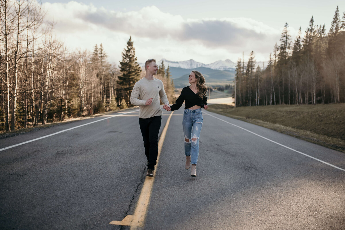 Man and woman running on road with mountains in the background