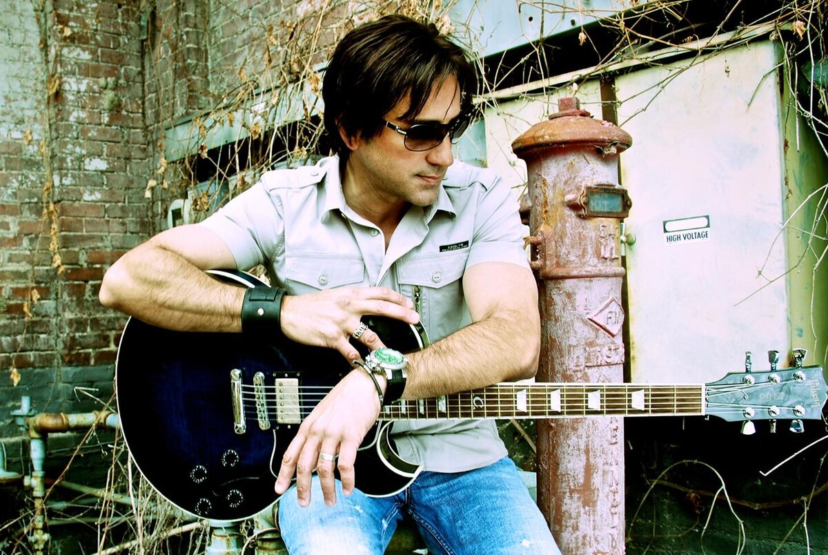 Steve Azar musician portrait seated outdoors holding guitar across his lap