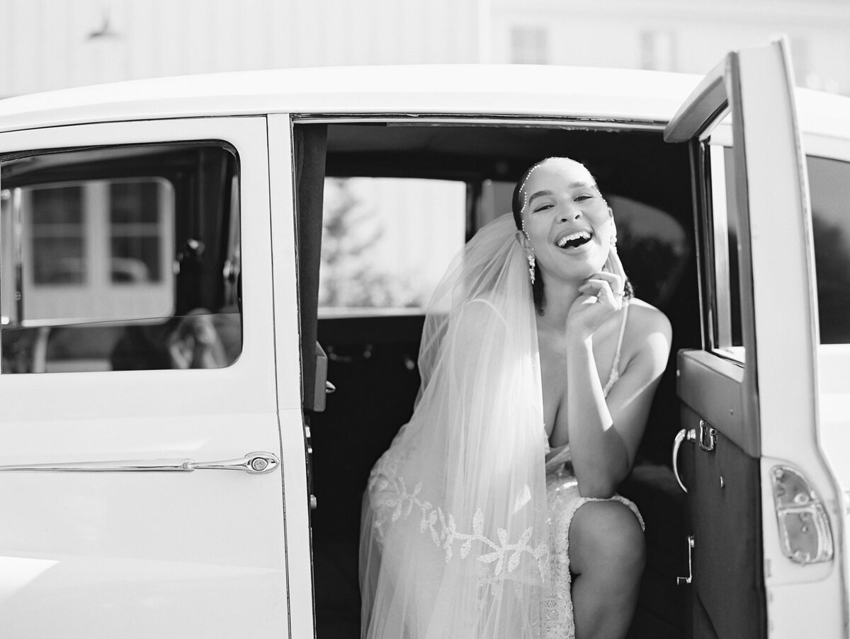 Bride laughing sitting in car photographed by Chicago editorial wedding photographer Arielle Peters
