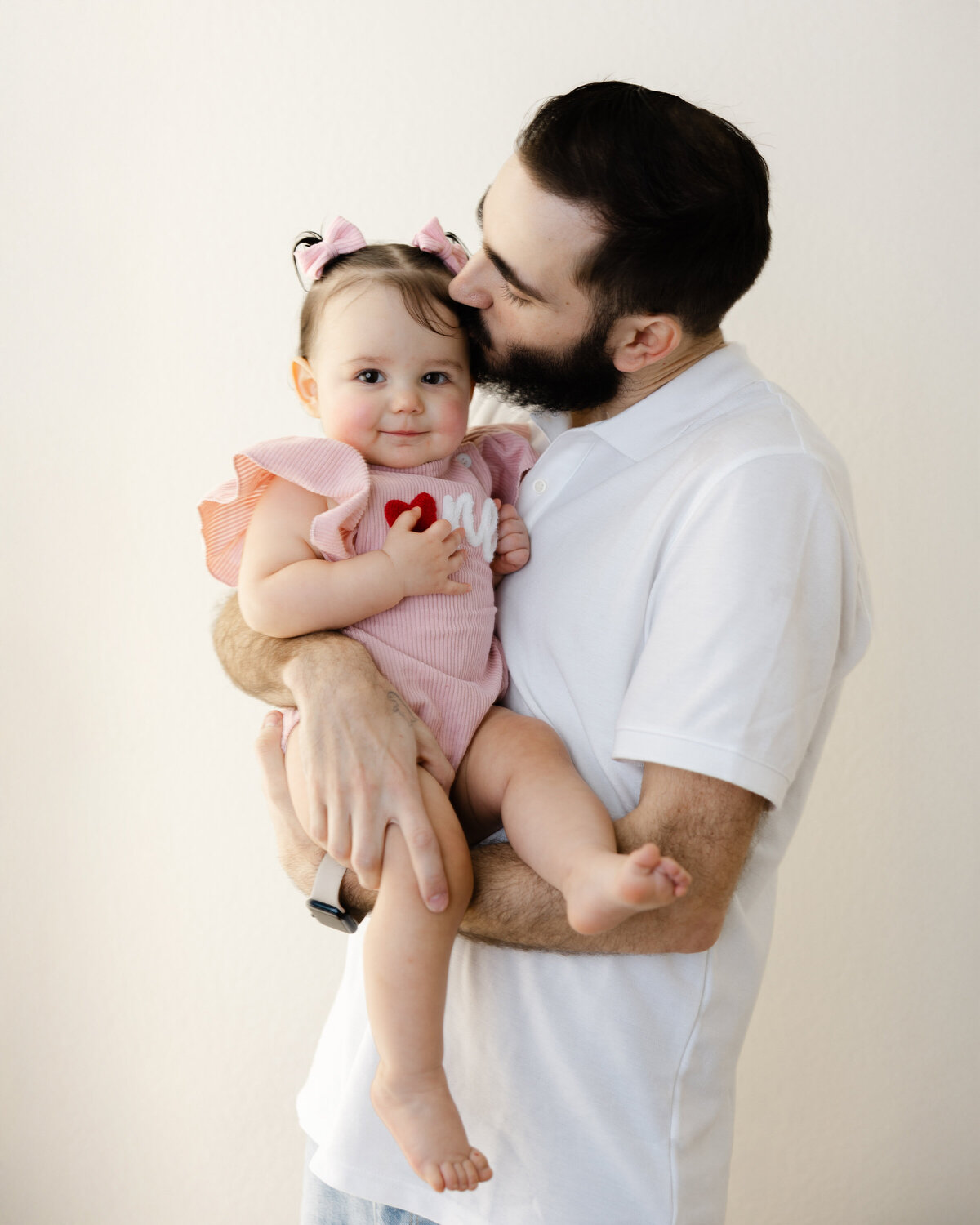 Celebrating his little girl with a kiss and a proud smile. Captured by Yucaipa cake smash photographer Kaitlyn Dawn Photography.