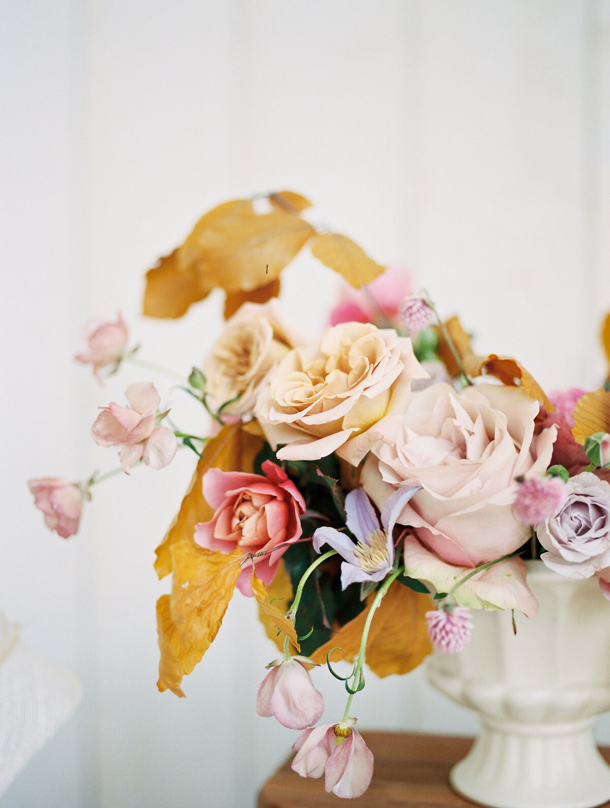 Closeup of floral centerpiece with pastel colors and pops of pink and goldenrod.