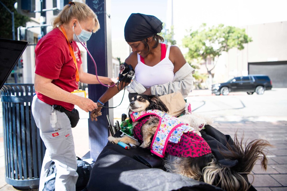 FJV team take blood pressure of women with dog who live on the street