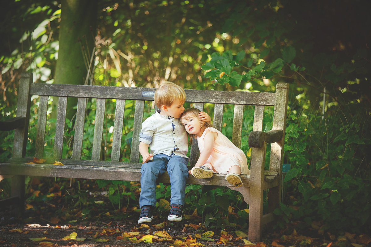 siblings cuddling on bench