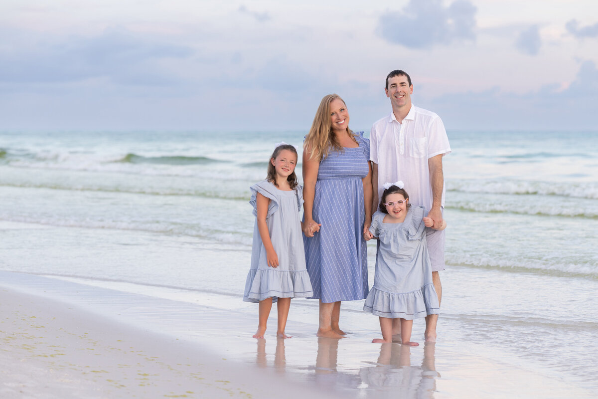 A family holding hands and standing in shallow water