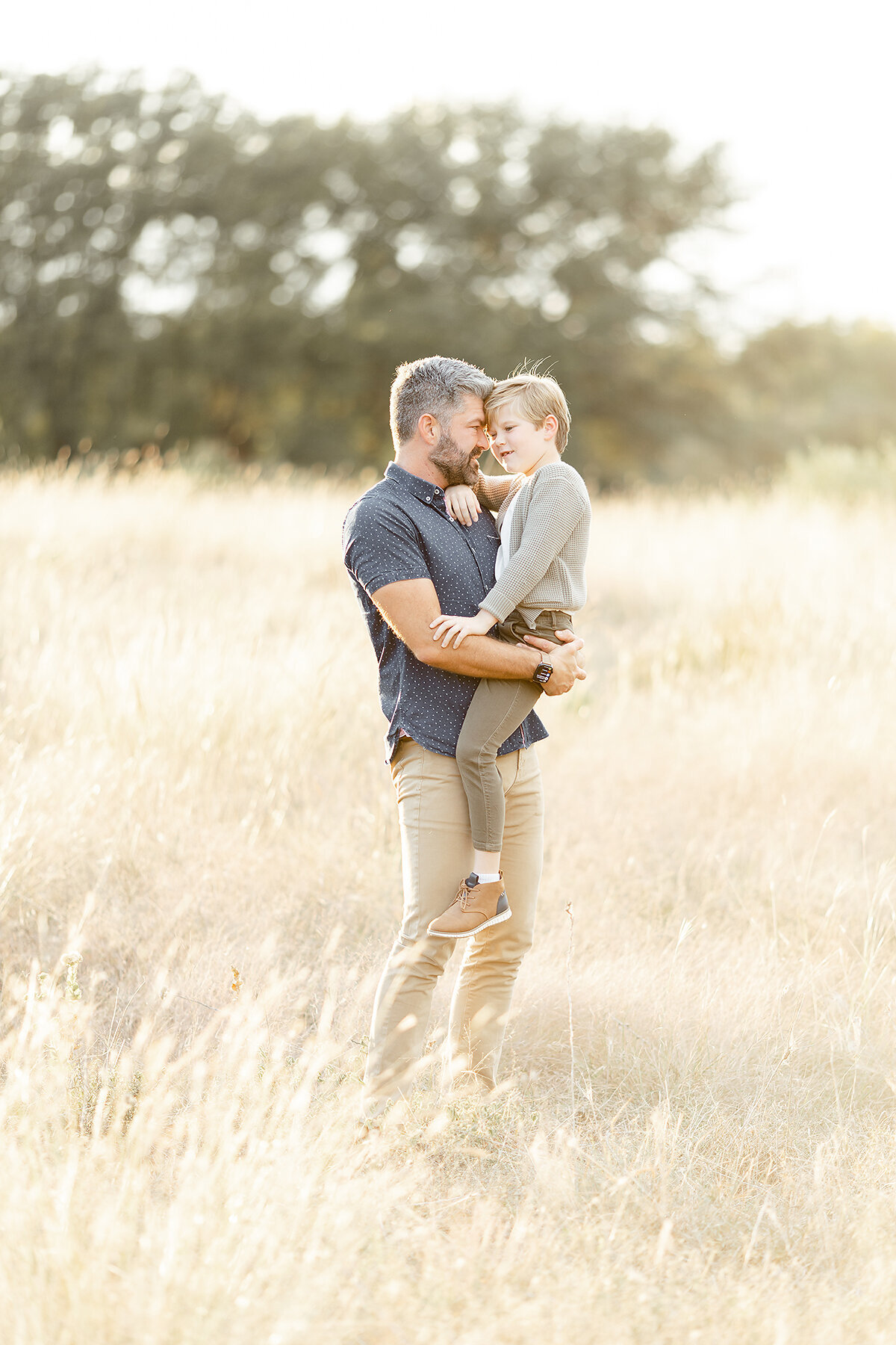 Photo of a father holding his son in the middle of a grassy field at a DWF park.