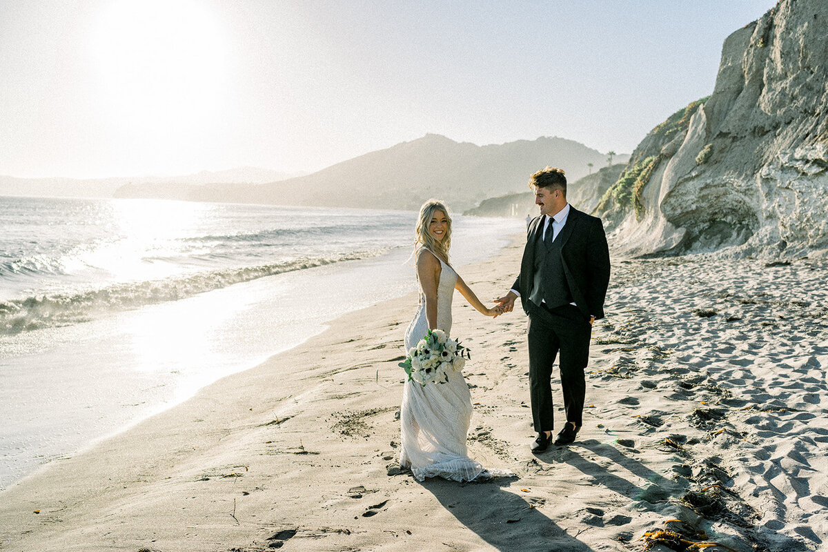 Bride and groom walking on the beach at Dolphin Bay Resort in Pismo Beach, CA