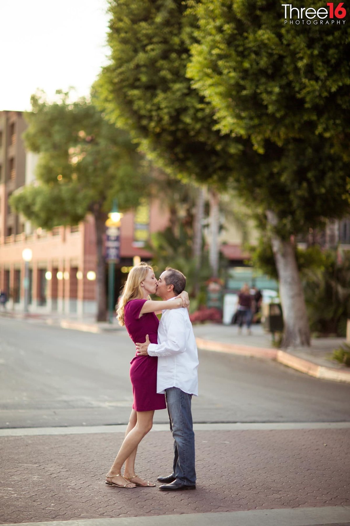 Engaged couple share a kiss in the middle of a downtown Fullerton street
