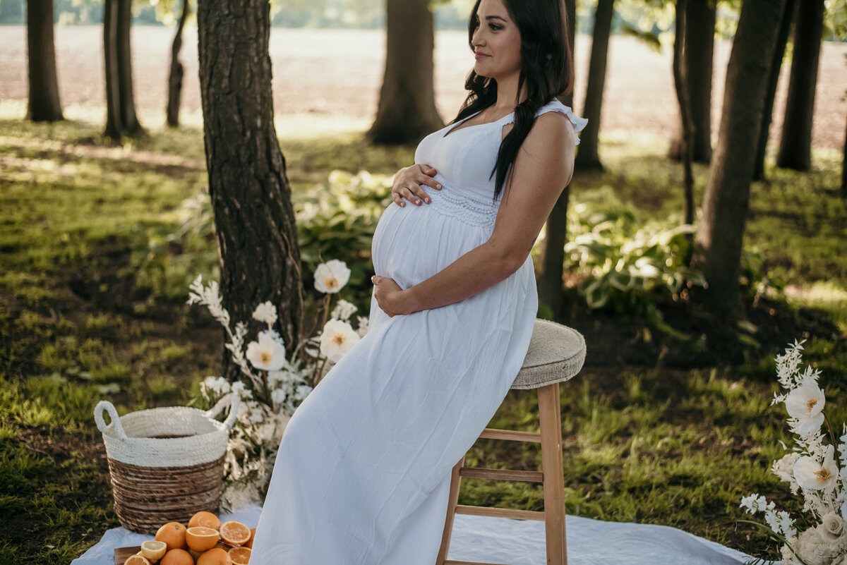 Pregnant woman on stool outside in white dress
