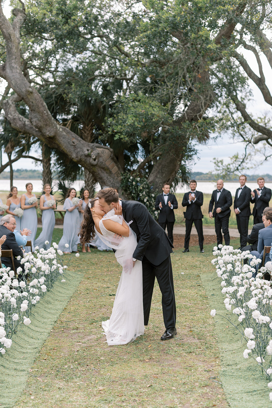 bride and groom kiss in wedding aisle