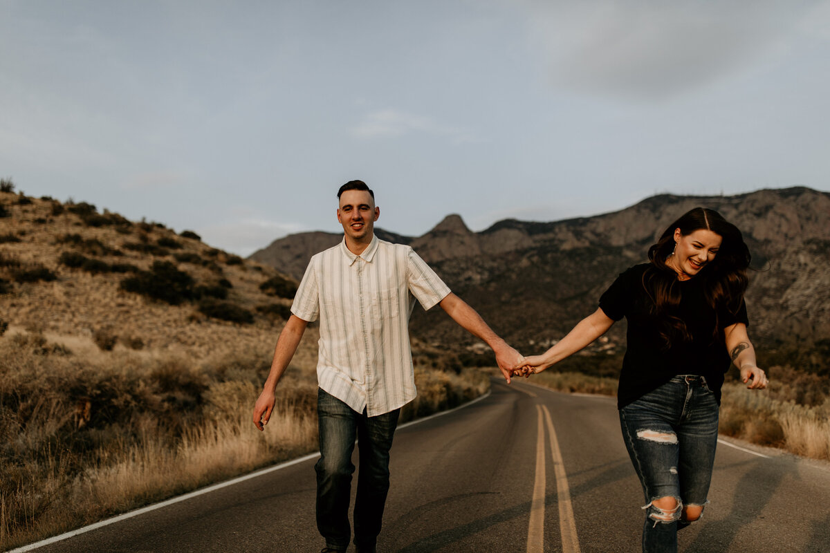engaged couple holding hands and running in the road