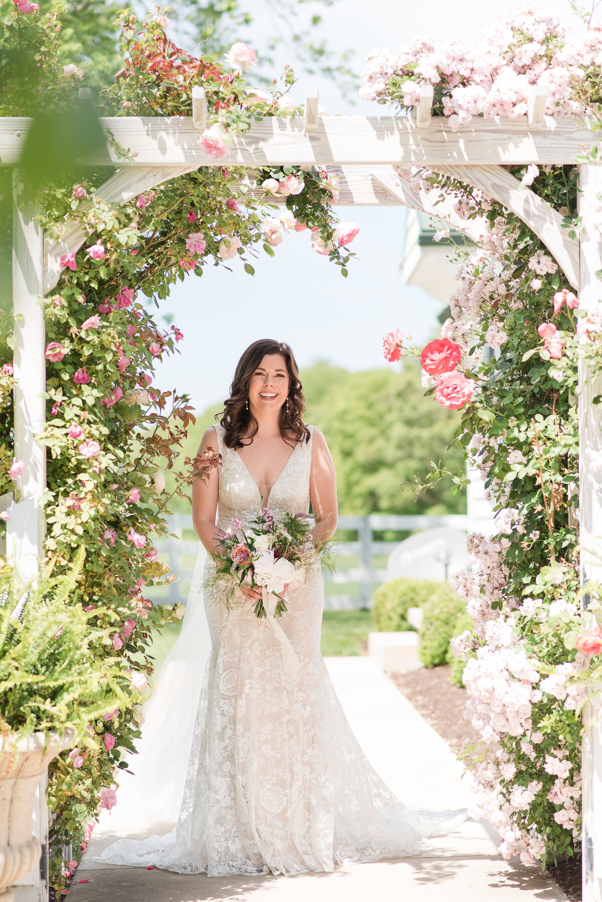 bride under an arch of flowers bluebird manor