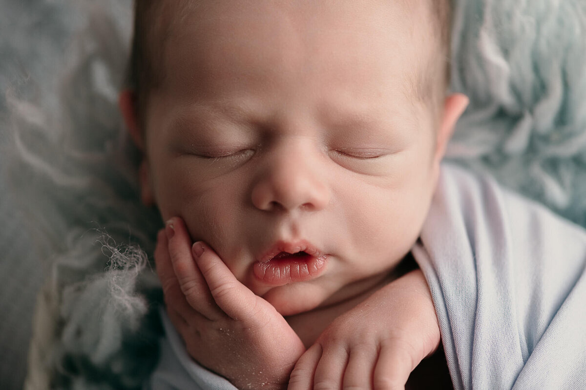 close-up photo of baby face, swaddled in light blue