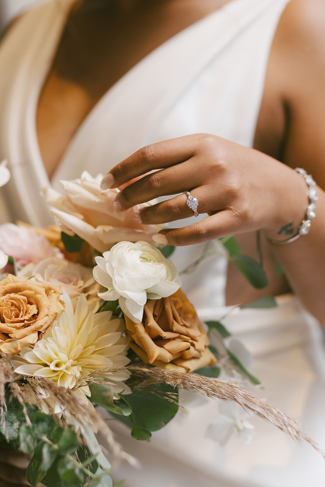Close up photo of bridal floral bouquet, engagement ring and elegant  gown at Loft on Lake wedding ceremony.