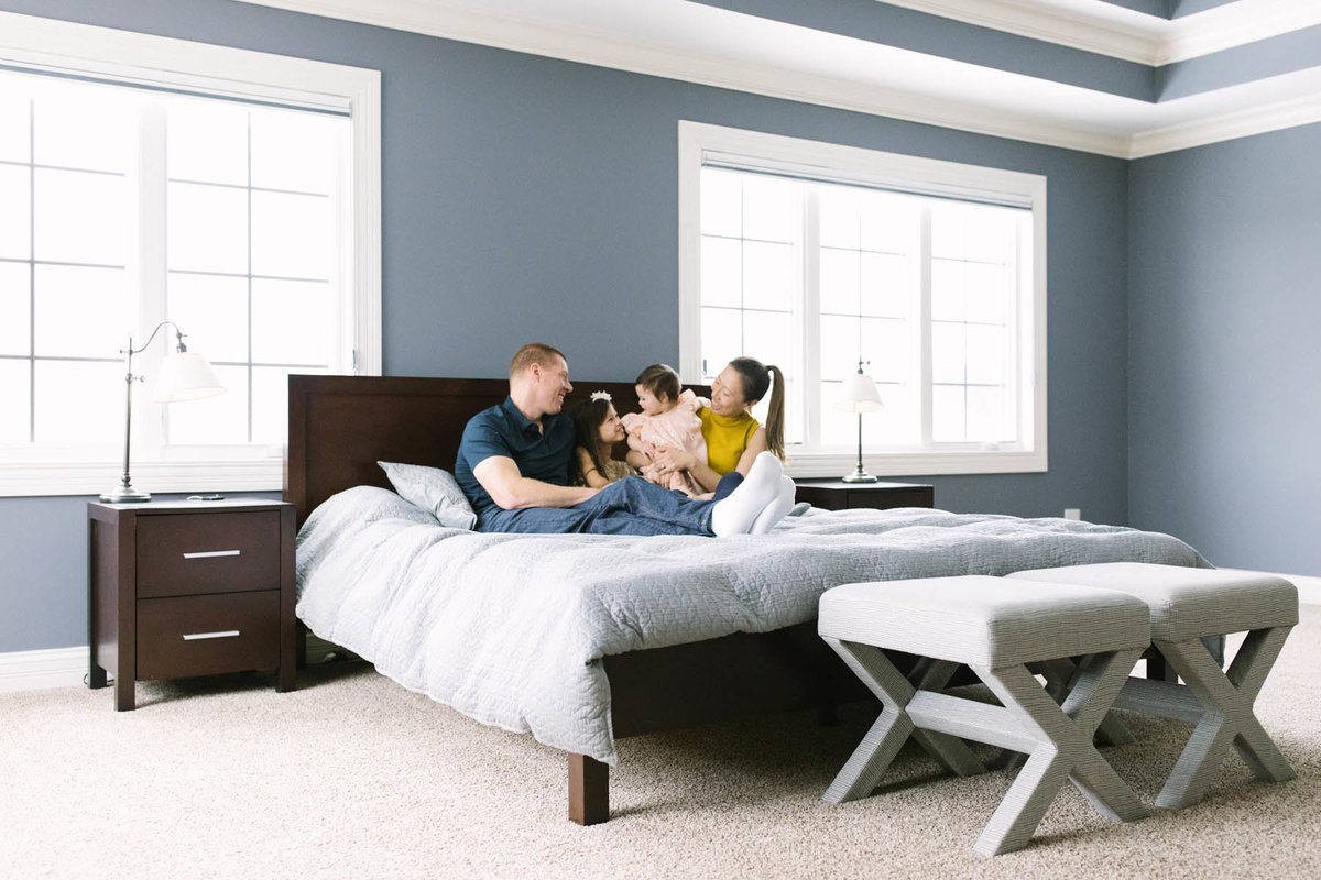 Family of four sitting on a bed