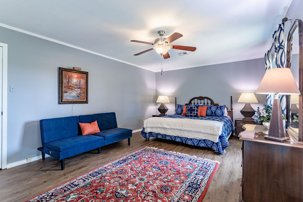 Spacious bedroom with cozy bedding and additional sofa seating in this 5-bedroom, 4-bathroom vacation rental house for 16+ guests with pool, free wifi, guesthouse and game room just 20 minutes away from downtown Waco, TX.