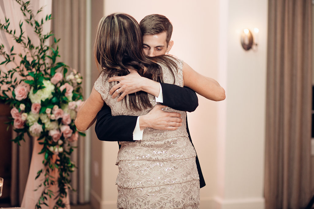 Wedding Photograph Of Groom In Black Suit And Woman  In Light Brown Dress Hugging Los Angeles