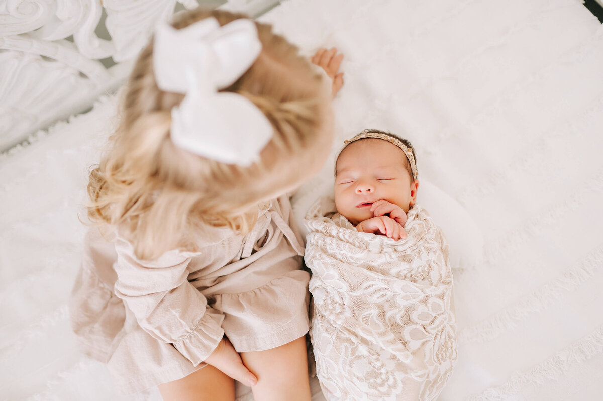 newborn picture in SpringfieldM O of toddler sister sitting by sleeping newborn sister