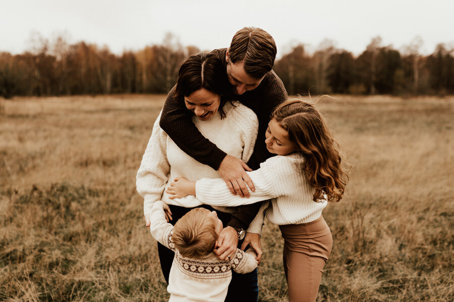 barn kramar om föräldrar under familjefotografering på en äng i halmstad