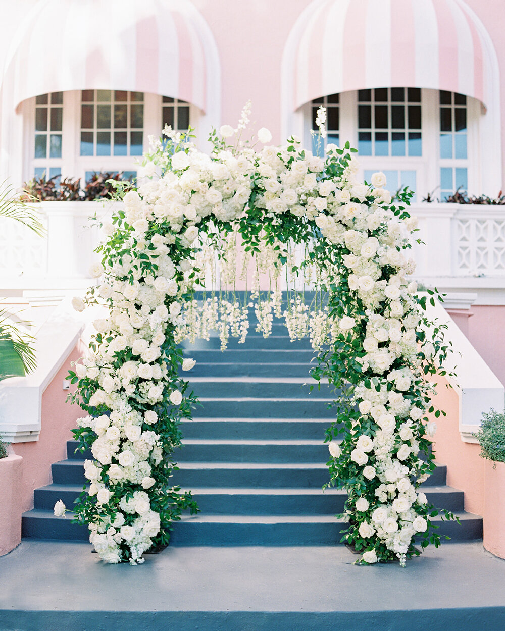 Dramatic floral arch with white flowers and dangling blooms in the courtyard of the Don Cesar Hotel, St. Pete Beach, Florida. Captured at a December wedding.