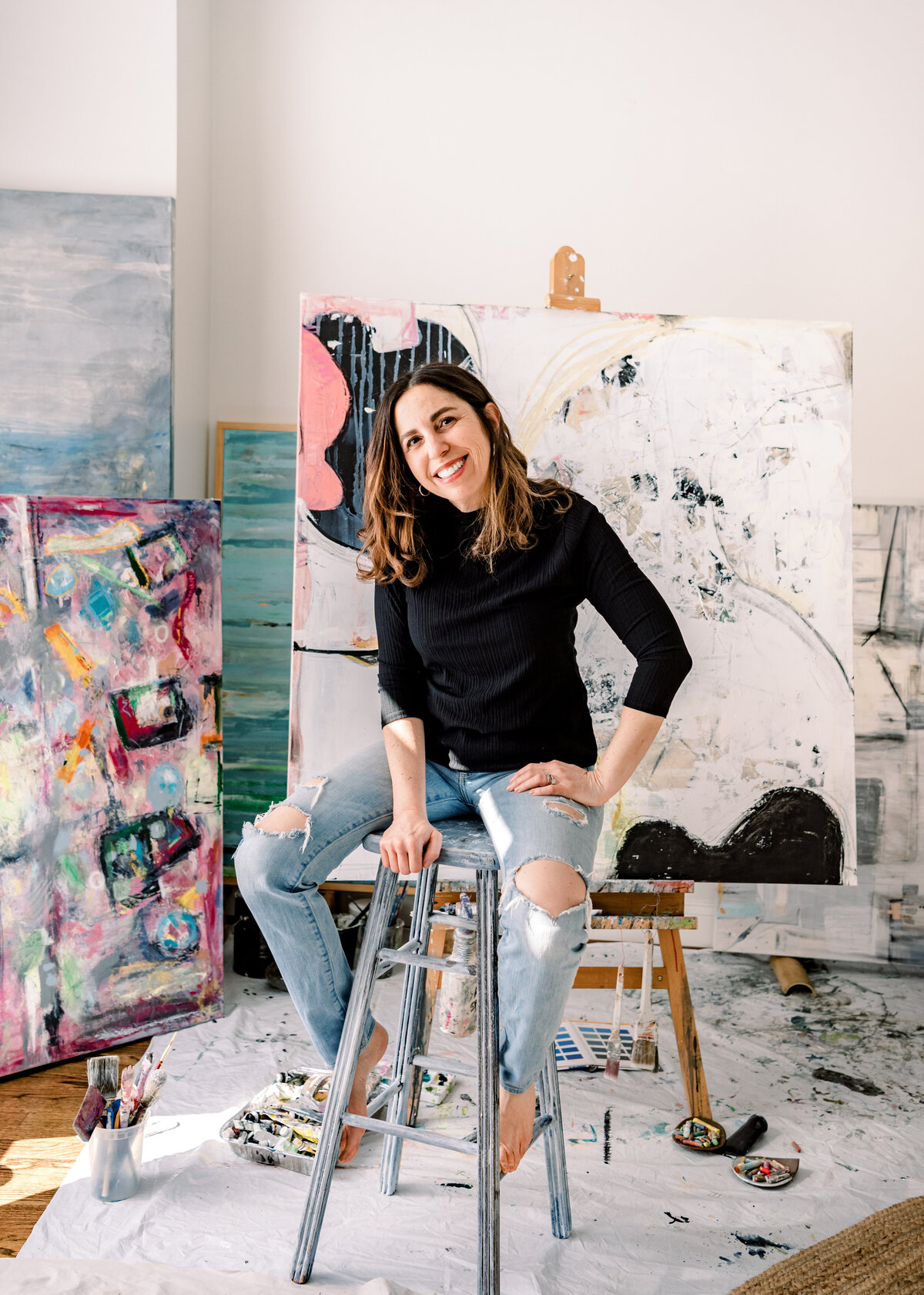 raleigh artist sits on stool in paint studio with large scale art
