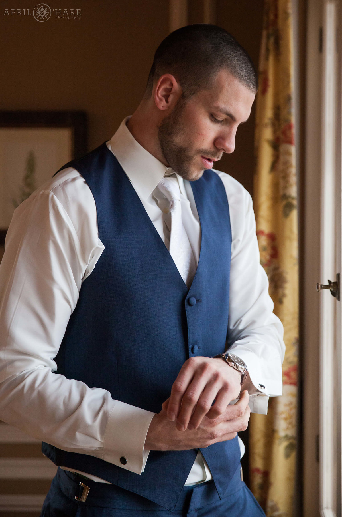 Groom dresses for wedding day at Highlands Ranch Mansion in Colorado