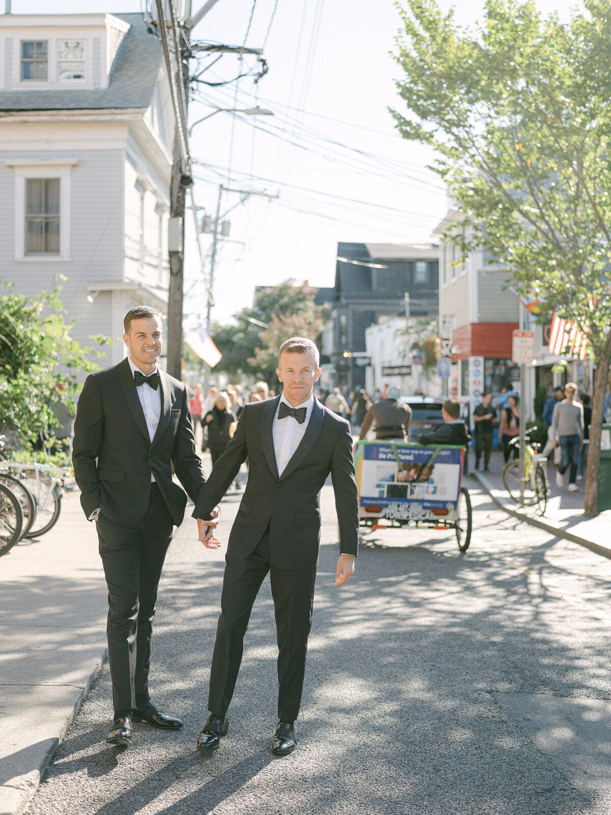Two grooms hold hands and walk down Commercial Street in Provincetown