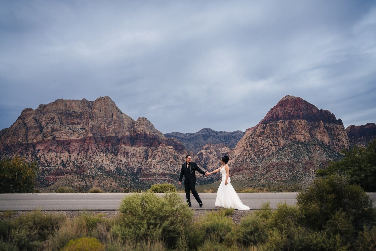 A picturesque scene of the couple strolling with the stunning red rocks of Las Vegas as the backdrop for their wedding photos, creating a breathtaking moment of love and nature's beauty.